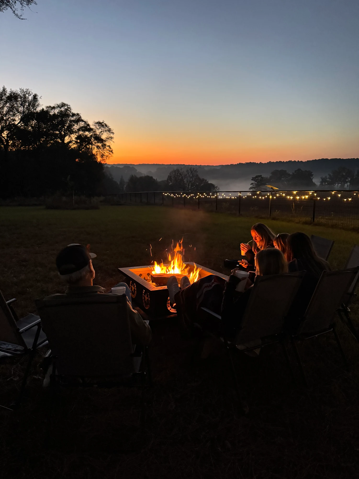 People gathered around the glowing firepit at dusk
