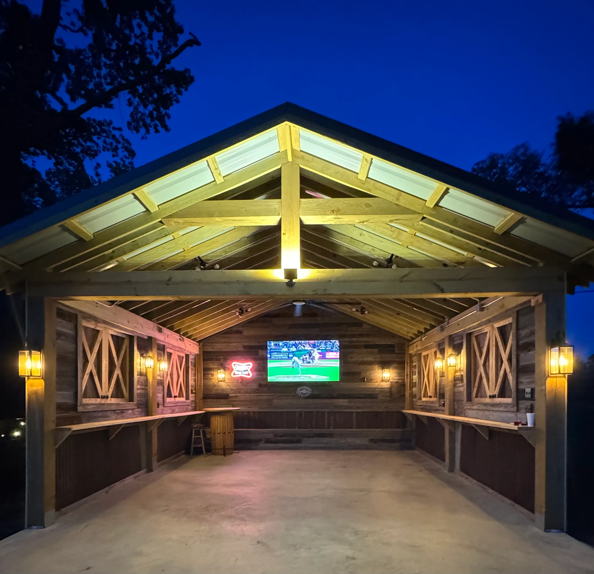 Illuminated party barn at dusk, with television and bar seating